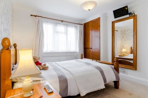 Deluxe Double Room at Brooklyn House B&B in Southgate, London with queen bed, wooden wardrobe, mirror, TV, and garden view