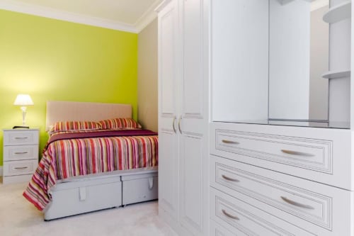 Bright Deluxe Queen Room at Brooklyn House with lime green accent wall, striped bedding, white wardrobe, and modern