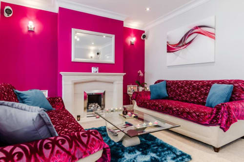 Vibrant pink living room at Brooklyn House B&B in Southgate, London with red sofas, fireplace, and modern decor.