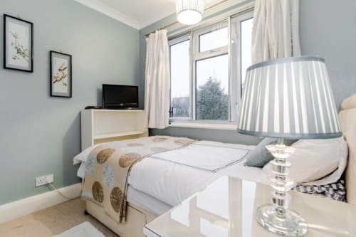 Modern bedroom at Brooklyn House B&B in Southgate, London with double bed, TV, striped lamp, and large windows