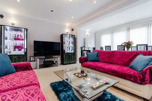 Modern living room at Brooklyn House Southgate with vibrant pink velvet sofas, teal accents, and glass coffee table