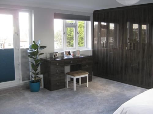 Spacious Deluxe Junior Suite at Brooklyn House showing dark wooden wardrobe, desk with garden views, blue potted plant, and