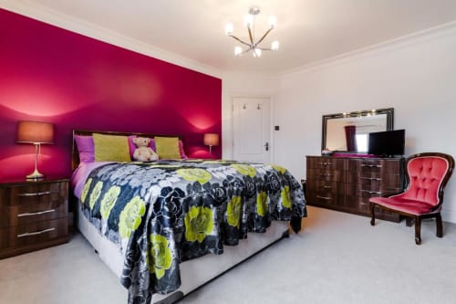 Modern bedroom at Brooklyn House B&B in Southgate, London with vibrant pink accent wall, floral bedding, and contemporary