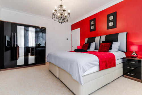 Luxury bedroom at Brooklyn House B&B in Southgate, London with red accent wall, white bedding, and black furniture