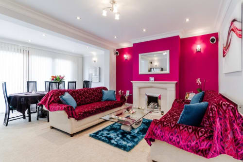 Vibrant pink living room at Brooklyn House B&B in Southgate, London with fuchsia sofas and fireplace