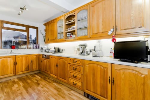 Warm wooden kitchen with white countertops, natural light, and countryside views at Brooklyn House B&B in Southgate, London