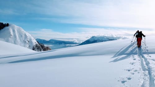 Sciatore di fondo su sentiero innevato alpino con vista della valle montagnosa vicino a Trento, Italia