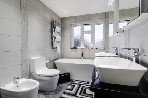 Modern bathroom at Brooklyn House BnB in Southgate London with double bathtubs, toilet and dual sinks