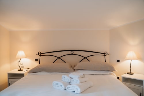 Camera elegante di Villa Del Sole Inn con testiera in ferro battuto, biancheria bianca, asciugamani arrotolati e illuminazione calorosa