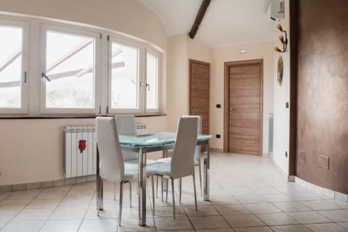 Zona pranzo moderna della Villa Del Sole Inn a Campobasso con vista montuosa, tavolo in vetro e porte in legno