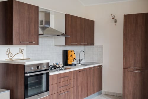 Cucina moderna dell'appartamento Villa Del Sole Inn a Campobasso con mobili in legno, elettrodomestici in acciaio inox e piastrelle bianche