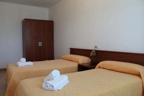 Habitación doble en Apartamentos Los Gemelos en Foz con dos camas, muebles de madera y toallas blancas
