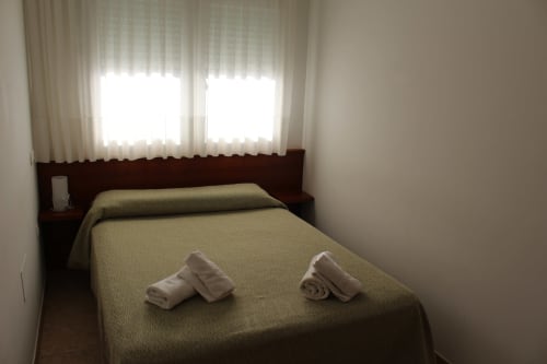 Habitación luminosa en Apartamentos Los Gemelos de Foz con camas gemelas, toallas blancas y cortinas translúcidas