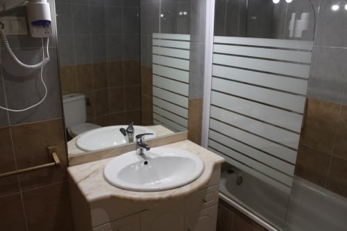 Baño moderno en Apartamentos Los Gemelos en Foz con lavamanos redondo, paredes alicatadas y cabina de ducha de cristal