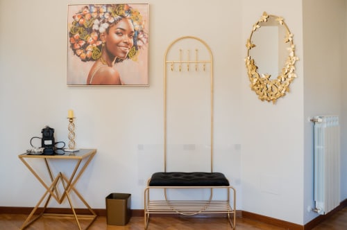 Elegante angolo camera da letto a Villa Del Sole Inn con opera d'arte, specchio dorato e arredamento moderno