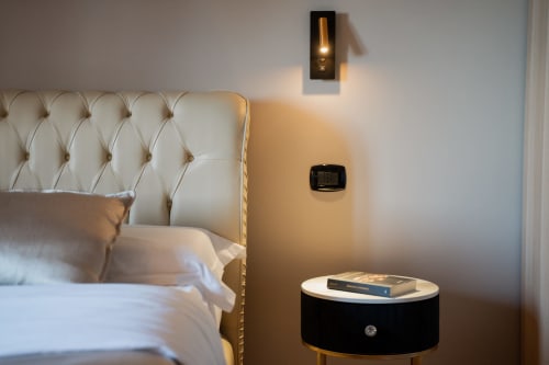 Elegante camera da letto della Villa Del Sole Inn con testata trapuntata, applique murale moderna e comodino nero a Campobasso