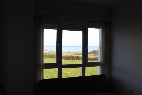 Vista desde el apartamento en Los Gemelos, Foz con campos verdes y paisaje costero a través de amplios ventanales