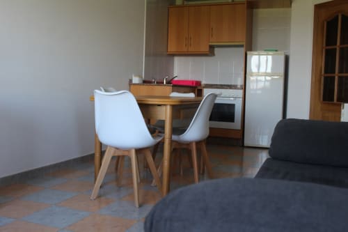 Cocina y comedor modernos de Apartamentos Los Gemelos en Foz, Lugo con mesa de madera, sillas blancas y