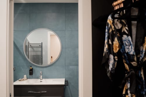 Bagno moderno a Villa Del Sole Inn con specchio circolare, lavabo bianco e piastrelle turchese a Campobasso