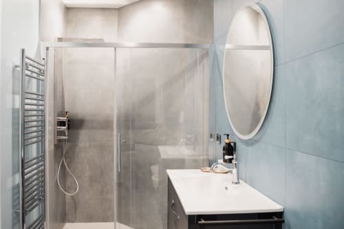 Bagno moderno di Villa Del Sole Inn con doccia in vetro, specchio rotondo e piastrelle blu