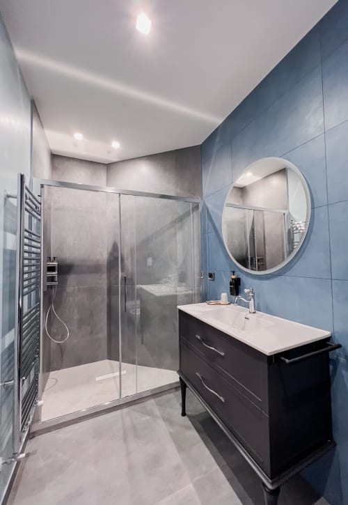 Bagno moderno di Villa Del Sole Inn con piastrelle blu, doccia walk-in, vanità nera e specchio rotondo