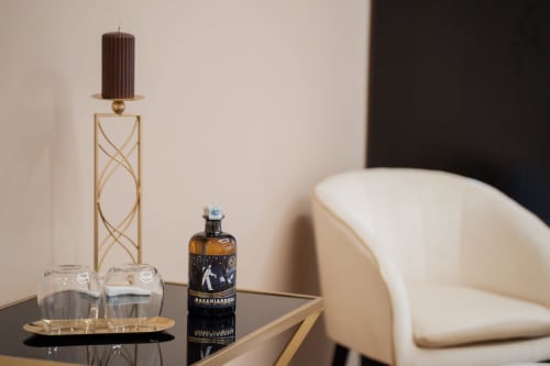 Dettaglio elegante della Villa Del Sole Inn con candelabro dorato, candela scura, bottiglia decorativa e sedia color crema