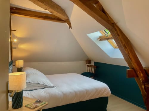 Chambre cosy sous les toits du Château de Vaux Morvan avec poutres apparentes, velux, literie blanche et mur d'accent teal