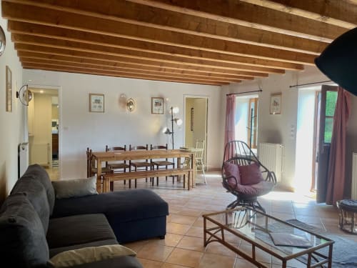 Spacieux séjour ouvert au Château de Vaux Morvan avec plafond à poutres apparentes, table à manger et assises confortables