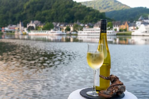 Glas Weißwein mit Flasche mit Blick auf den Fluss Remiremont und bewaldete Hügel im Grand Bienfaisy