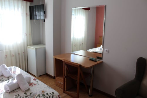 Habitación del Hotel Rego Foz con cama, escritorio, espejo, TV, refrigerador y ventana en Lugo, España