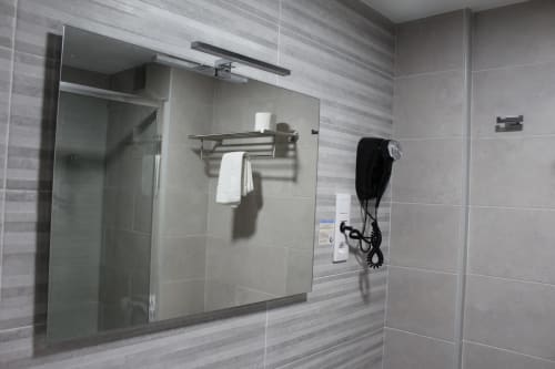 Baño moderno del Hotel Rego Foz con azulejos grises, ducha de cristal y servicios hoteleros en Foz, Lugo