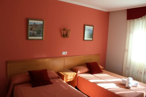 Dormitorio coral brillante en Hotel Rego Foz de Foz, Lugo, con camas gemelas, cabecero de madera y cuadros enmarcados