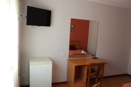 Habitación del Hotel Rego Foz con TV, minibar, escritorio de madera con espejo y pared roja en Lugo, España