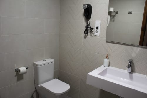 Baño moderno del Hotel Rego Foz en Foz, Lugo con lavamanos blanco, inodoro y paredes con azulejos en espiga