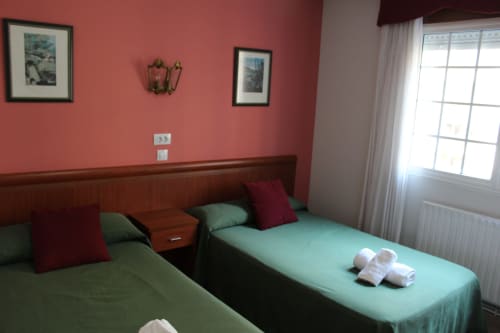 Habitación doble del Hotel Rego Foz en Foz, Lugo con paredes color coral, cabecero de madera y camas verde menta