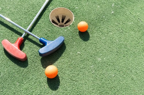 Colorful mini golf setup at Brooklyn House with putters, orange balls, and hole at Southgate, London B&B