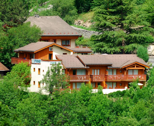 Hôtel Studios La Rochetaillée niché dans une végétation luxuriante, Brides-les-Bains, architecture alpine aux teintes ocre-brun