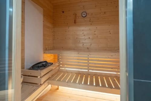 Interior de sauna em madeira na Casa Da Colina com bancos, elementos de aquecimento e relógio em Caldas De Monchique