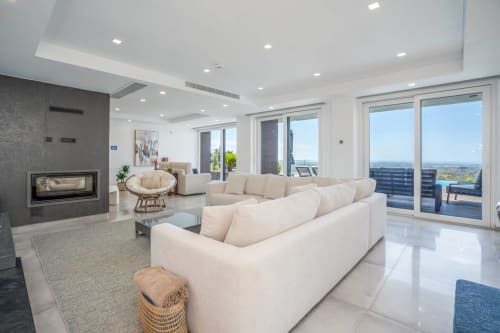 Moderna sala de estar da Casa Da Colina com sofás creme, lareira e vistas panorâmicas da zona rural de Caldas de Monchique