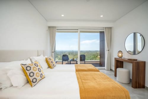 Quarto moderno na Casa Da Colina com vistas panorâmicas do vale, roupas de cama brancas, detalhes em ouro e móveis contemporâneos