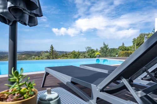 Espreguiçadeiras junto à piscina de borda infinita do hotel Casa Da Colina em Caldas De Monchique, Portugal, com vista para a paisagem exuberante