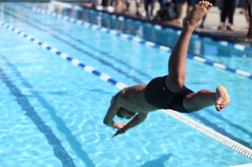 Young swimmer diving into blue lap pool at Brooklyn House B&B in Southgate, London