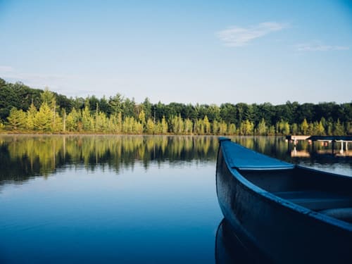 Blue rowboat on calm lake with forest reflections, peaceful waterside setting
