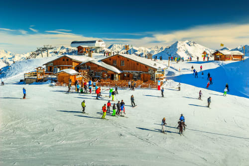 Ski resort with wooden chalets, snowy slopes, and skiers in Brides-les-Bains, French Alps