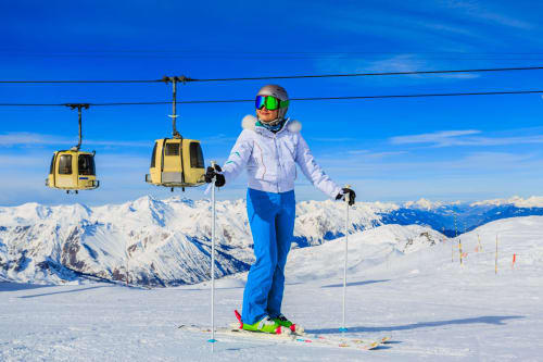 Skier at Brides-les-Bains resort with cable car and snow-covered Alps in background