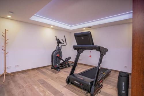 Moderno ginásio caseiro na villa Casa Da Colina com esteira, bicicleta elíptica, cabideiro de madeira e claraboia em Portugal