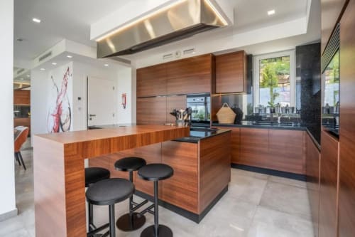 Cozinha moderna na villa Casa da Colina com armários de madeira, ilha de trabalho, eletrodomésticos de aço inoxidável e vistas para o mar