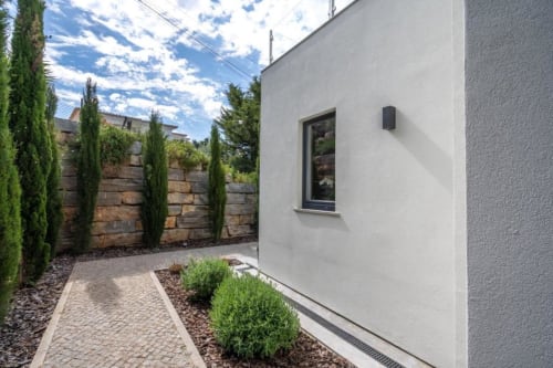 Pátio de villa moderna em Casa Da Colina com paredes brancas, cerca de pedra, ciprestes, caminho pavimentado e paisagismo do jardim