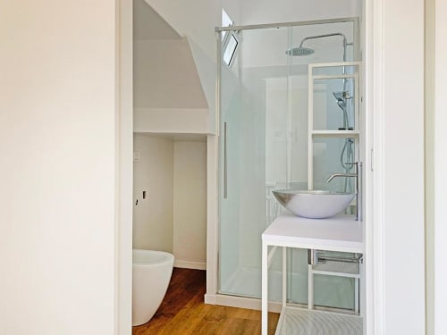 Bagno moderno con box doccia in vetro, lavabo a bacinella e pavimentazione in legno all'interno dell'appartamento Residence Balconi del Conero
