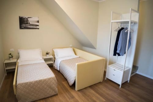 Suite luminosa presso Residence Balconi del Conero con due letti singoli, pavimento in legno, guardaroba bianco e vista costiera